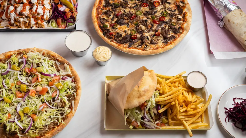 Pizza, kebabtallrik, rulle och burgare på samma bord